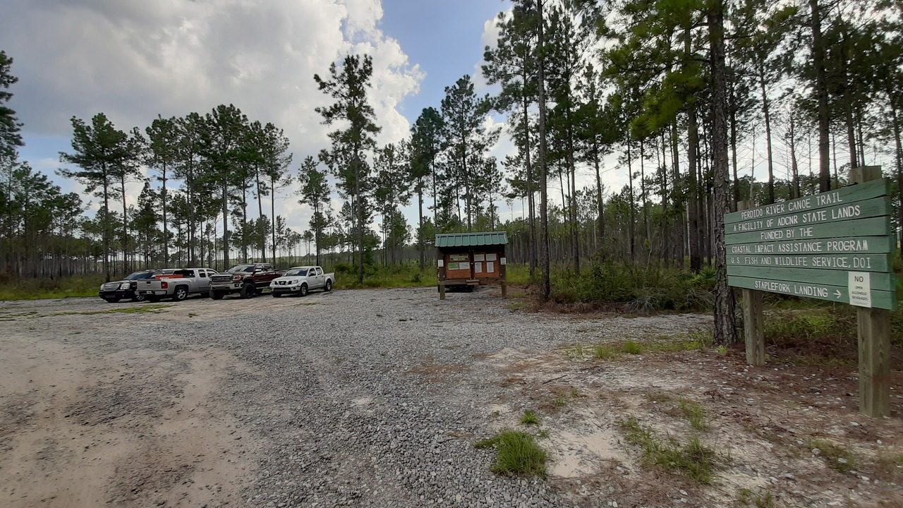 Gravel parking lot with trucks at Staple Fork Landing trailhead